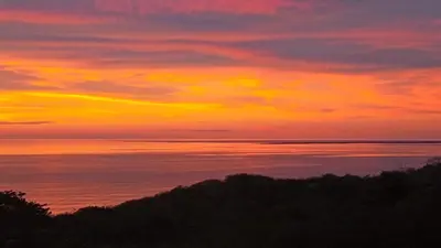 a sunset over the ocean with trees in the foreground at Kamajorú Ecohabitat in Tubará