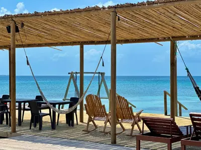a porch with chairs and a swing on the beach at Medusa Hostel Isla Tintipan in Tintipan Island