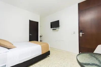 a bedroom with a bed and a tv on the wall at Hotel Med Suites 94 in Barranquilla
