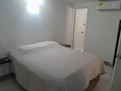 a bedroom with a white bed with a white bedspread at Condominio en la Playa de Crespo in Cartagena de Indias