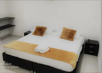 a bedroom with a large bed with white sheets and brown pillows at Hotel Don Jose in Ciénaga