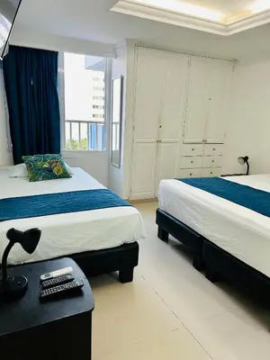 a bedroom with two beds and a desk and a window at Apartamento in Cartagena de Indias