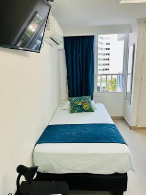 a bedroom with a bed with a blue curtain and a window at Apartamento in Cartagena de Indias