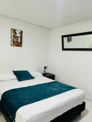 a white bedroom with a bed with a blue blanket at Apartaestudio in Cartagena de Indias