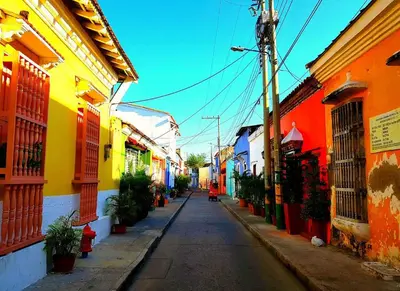 a narrow street with colorful buildings on either side at 2CB-3 APARTAMENTO DE 2 ALCOBAS EN EL CENTRO HISTORICO CON AIRE ACONDICIONADO Y WIFI in Cartagena de Indias