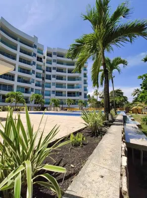 a large building with palm trees and a sidewalk at Acogedor apartamento con vista al mar en coveñas in Coveñas