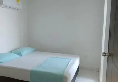 a bedroom with a white bed with blue pillows at Apartamento 3 Carabelas Cartagena Piso 16 in Cartagena de Indias
