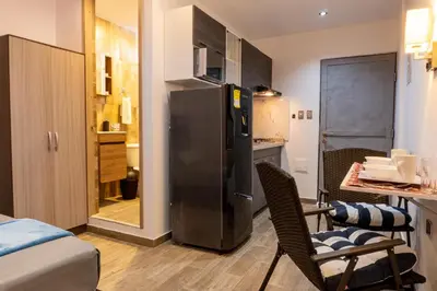 a kitchen with a refrigerator and a table and chairs at Confort+Relax= Romántico ApartaEstudio + Piscina + Parqueadero in Santa Marta