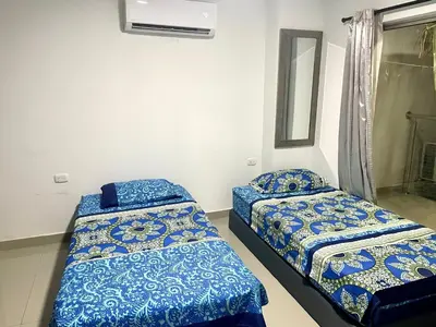 two beds in a room with blue sheets at Apartamento en el epicentro del Carnaval in Barranquilla