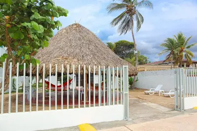 a gazebo with chairs and a thatch roof at Cabaña Macondo in Coveñitas