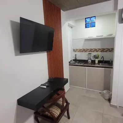 a living room with a table and a television on a wall at Hostal Casa Marle in Puerto Colombia