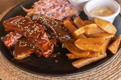 a plate of food with ribs and potato fries at CasaCoral Hotel in Isla Fuerte