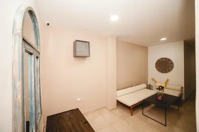 a living room with a bench and a clock on the wall at Abel Boutique House in Cartagena de Indias