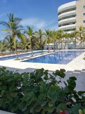 a swimming pool with palm trees and a building at APARTAMENTO MORROS922 LA BOQUILLA con acceso directo a la Playa in Cartagena de Indias