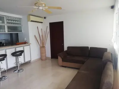 a living room with a brown couch and a kitchen at APARTAMENTO MORROS922 LA BOQUILLA con acceso directo a la Playa in Cartagena de Indias