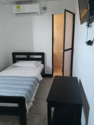 a bedroom with a bed and a black table at HOTEL LOS GUADUALES in Barranquilla