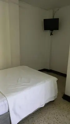 a white bed in a room with a tv on the wall at HOTEL LOS GUADUALES in Barranquilla