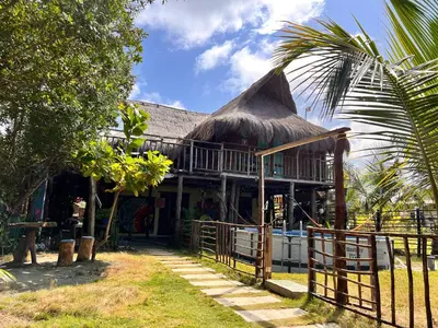 a building with a thatch roof and a fence at Arcoiris EcoHotel in San Bernardo del Viento
