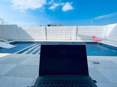 a laptop computer sitting next to a swimming pool at Casita Madrigal in Santa Veronica