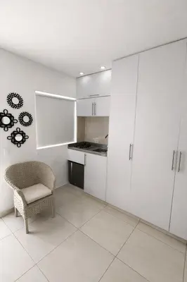 a kitchen with white cabinets and a chair in a room at Aparta estudios Mubarak in Barranquilla