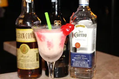 a drink in a martini glass next to bottles of alcohol at VAIA HOTELES in Coveñas