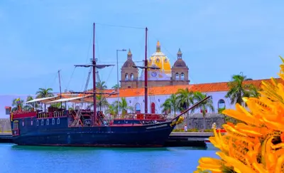 a boat sitting in the water in front of a building at Beach Villa Sol & Mar Cartagena, beachfront & private pool in Cartagena de Indias