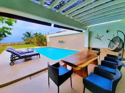 a patio with a table and chairs and a swimming pool at Beach Villa Sol & Mar Cartagena, beachfront & private pool in Cartagena de Indias