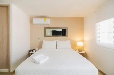 a bedroom with a white bed and a window at Bahari Cartagena Suites in Cartagena de Indias