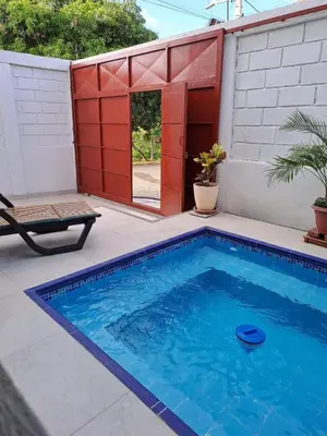a small swimming pool in a backyard with a red door at Rancho Ayala II in Santa Marta