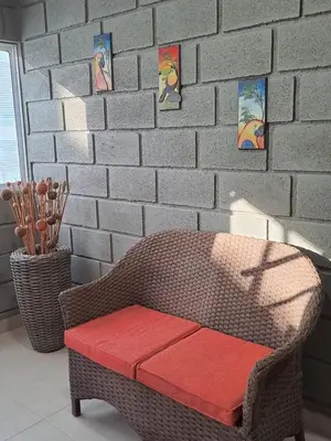 a wicker chair with a red bench in front of a brick wall at Rancho Ayala II in Santa Marta