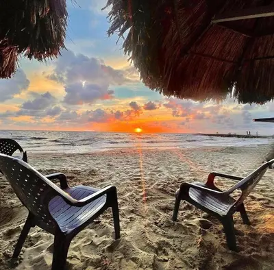 two chairs sitting on a beach with the sunset at Condominio, Cabaña 202 in Puerto Viejo