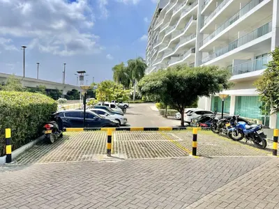 a parking lot with cars and motorcycles parked next to a building at Beachfront Bliss-2BR Haven Steps from Sandy Shores in Cartagena de Indias