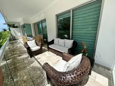 a patio with a couch and chairs on a balcony at Beachfront Bliss-2BR Haven Steps from Sandy Shores in Cartagena de Indias