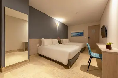 a bedroom with a large white bed and a desk at Hotel Rilux Cartagena in Cartagena de Indias