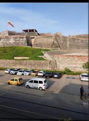 a parking lot with cars parked in front of a wall at casa castillo san felipe in Cartagena de Indias