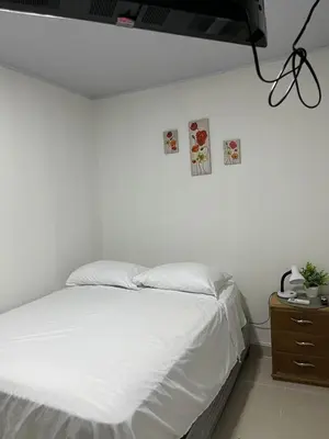 a bedroom with a white bed and a wooden dresser at Hospedaje Casa Pachi en Cartagena de Indias in Cartagena de Indias