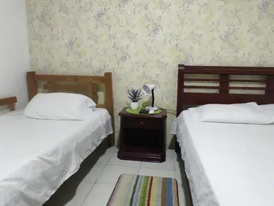 a bedroom with two beds and a table with a lamp at Hospedaje Casa Pachi en Cartagena de Indias in Cartagena de Indias