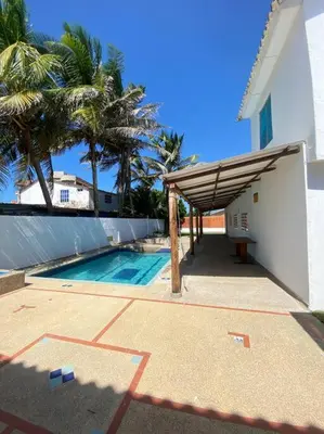a swimming pool with a wooden awning next to a house at Cabaña con piscina y Cerca al mar VILLA CONEJO in Juan de Acosta