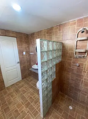 a bathroom with a toilet and a tiled wall at Cabaña con piscina y Cerca al mar VILLA CONEJO in Juan de Acosta