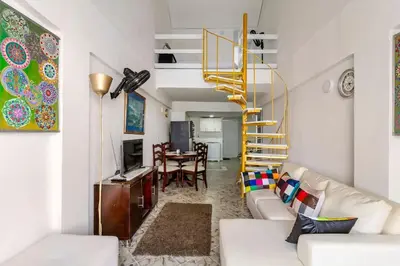 a living room with a white couch and a yellow spiral staircase at Apartamento cerca al Mar in Cartagena de Indias