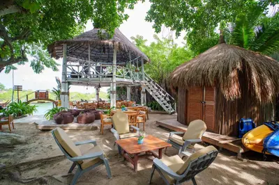 a restaurant with chairs and a table and a hut at Isla Mulata, Islas del Rosario in Isla Grande