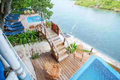 a deck with stairs and chairs next to a swimming pool at Isla Mulata, Islas del Rosario in Isla Grande