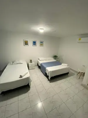 two beds in a room with white walls at Habitación cerca al aeropuerto 1 in Cartagena de Indias