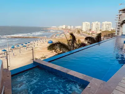 a swimming pool with the beach in the background at Front beach apartment close to the Cartagena letters in Cartagena de Indias
