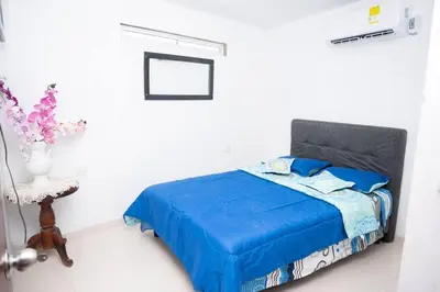 a bedroom with a blue bed in a white room at cabaña villa Oti 1 in Ciénaga