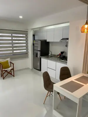 a kitchen with white cabinets and a table and chairs at Apartasuites Mardini in Cartagena de Indias