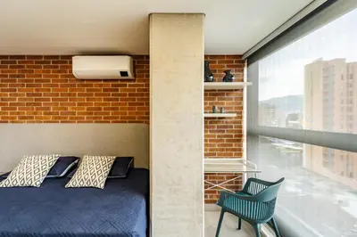 a bed and a chair in a room with a brick wall at Apartamento ubicado en, LAURELES, MEDELLIN in Cartagena de Indias
