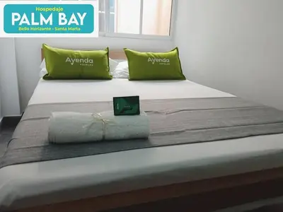 a bed with green pillows and avertisement for at SGH Hotel Palm Bay Bello Horizonte in Santa Marta