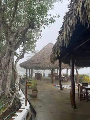 a resort with tables and straw umbrellas on the beach at Ecohotel La Reserva in Piojó