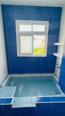 a blue tiled bathroom with a tub with a window at AzulRest Casa de Verano in Santa Veronica